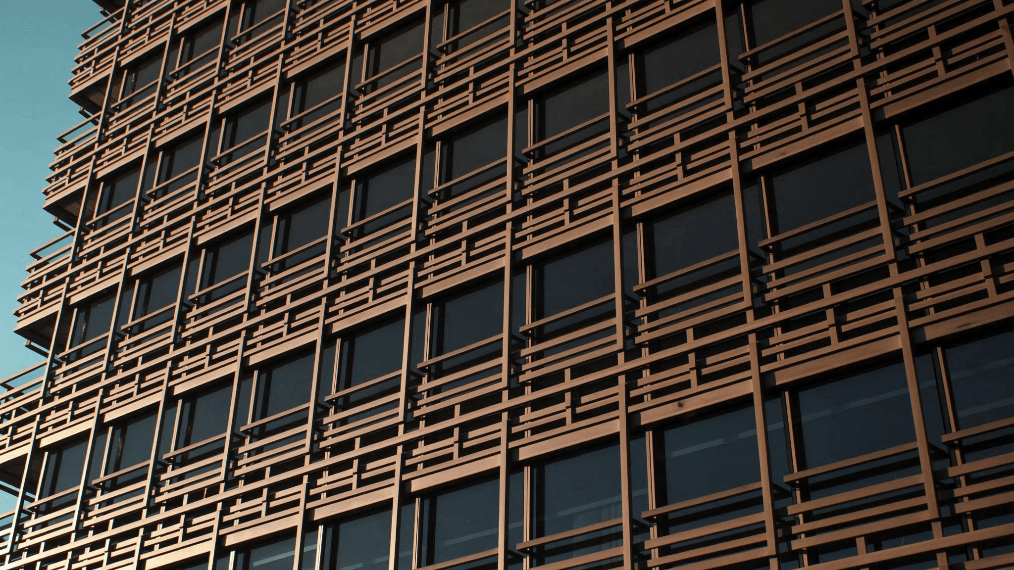Untersicht einer geflochtenen Bronze-Fassade vor blauem Himmel